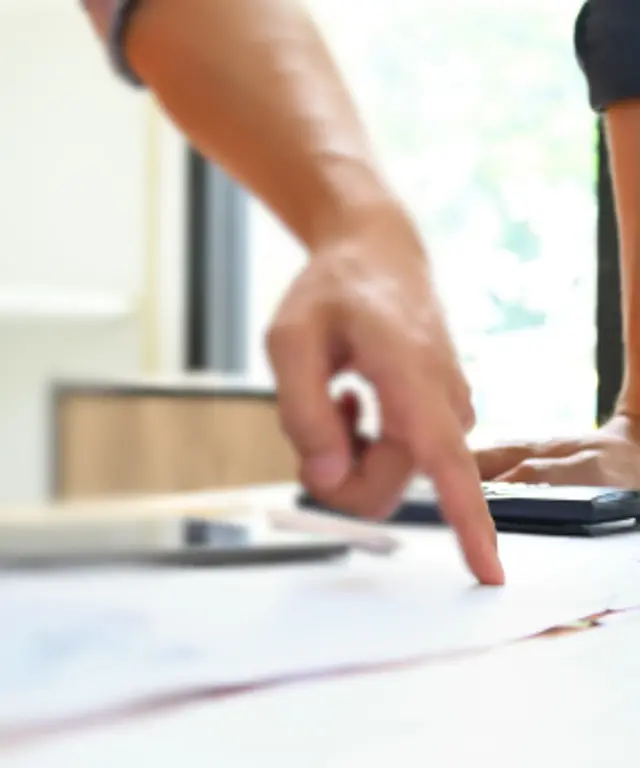 Bauarbeiter in Warnwesten diskutieren über Baupläne und zeigen auf Zeichnungen – Zusammenarbeit und Projektkoordination auf der Baustelle.