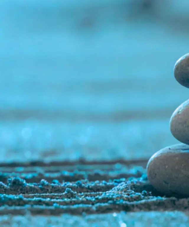 Drei glatt geschichtete Zen‑Steine auf leicht gerilltem Sand – Symbol für drei Möglichkeiten.