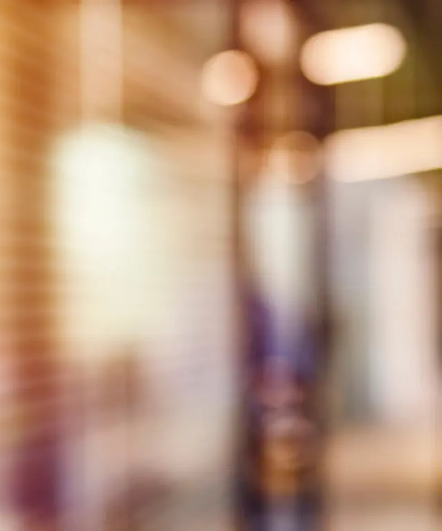 Unscharfer moderner Büroflur mit warmem Licht und Glaswänden – abstrakte, professionelle Hintergrundszene für Business‑Themen.