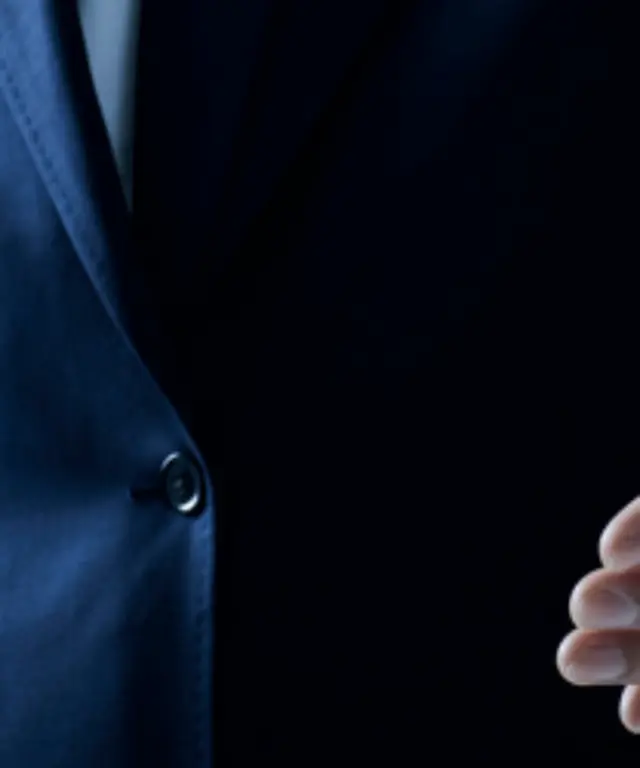 Geschäftsmann im dunklen Anzug streckt die Hand zum Handschlag aus – Symbol für Begrüßung, Partnerschaft und Zusammenarbeit