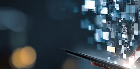 Finger tippt auf ein Tablet, während digitale Daten‑ und Interface‑Elemente holografisch aufsteigen – Symbol für moderne Technologien und Digitalisierung